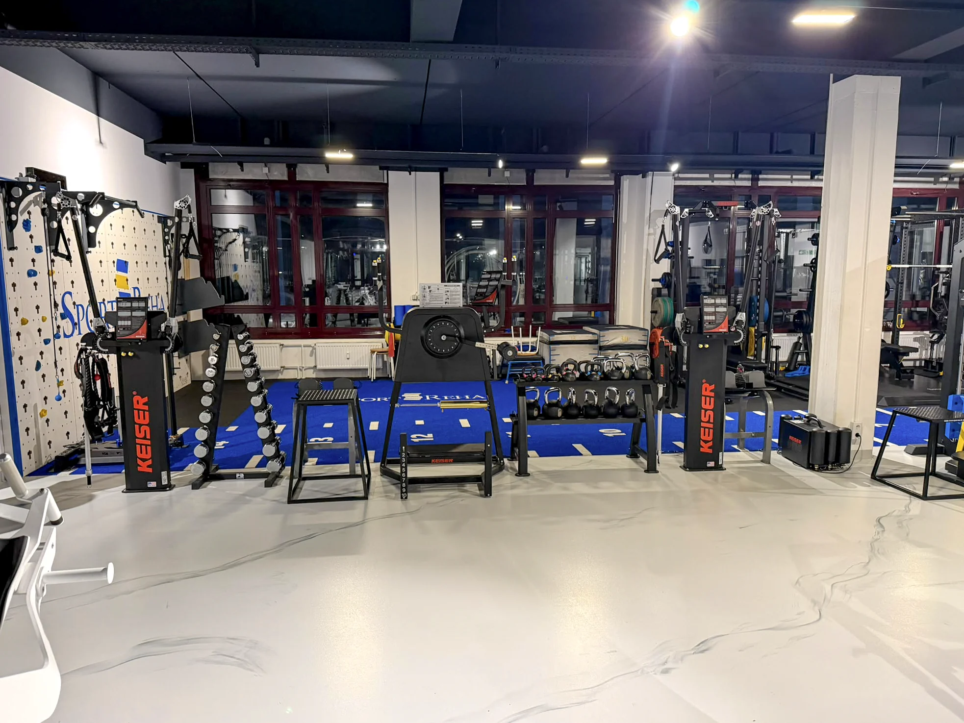 Kraftbereich mit Geräten und blauer Trainingsbahn in der Sport-REHA Berlin